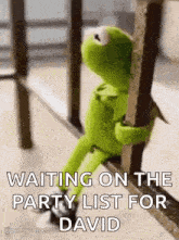 kermit the frog is sitting on a railing and holding a pole .