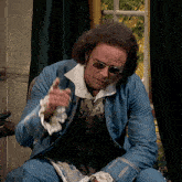 a man in a blue suit and sunglasses is sitting in a chair