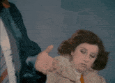 a woman in a white coat and orange tie is being held by a man in a black jacket