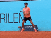 a man is holding a tennis racquet in front of a sign that says rilen