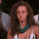 a woman with curly hair and a green scarf around her neck is sitting in a group of people .