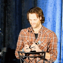 a man in a plaid shirt is holding a microphone in his hands