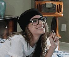 a woman wearing glasses and a beanie is smiling