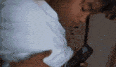 a man in a white shirt holds a cell phone in his hand