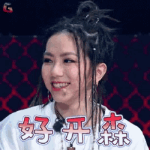 a woman with dreadlocks is smiling in front of a chinese sign