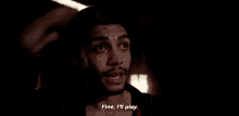 a man with a beard is standing in a dark room and saying `` fine , i 'll play . ''
