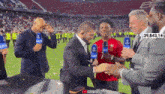 a man in a suit is shaking hands with a man in a red shirt with the number 39,843,147 on it