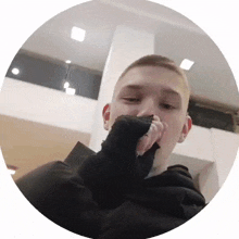 a young man covering his mouth with his hand in a circle .