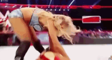 a woman in a bikini is wrestling another woman in a ring .