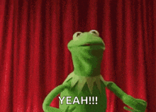 kermit the frog is dancing on a stage in front of a red curtain and saying yeah .
