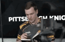 a man in a pittsburgh cu knic jersey is holding a book