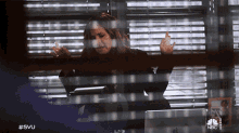 a woman sitting in front of a window with a nbc logo on the bottom