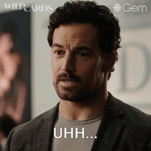 a man with a beard says " uhh " in front of a poster for wildcards
