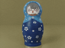a blue green and orange nesting doll with white flowers on them
