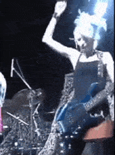 a woman playing a guitar on a stage with her hand in the air