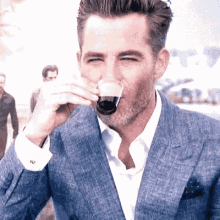 a man in a suit drinking from a glass