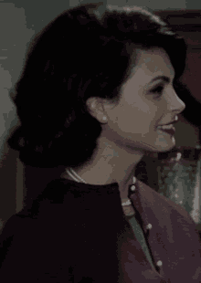 a woman in a pearl necklace kisses a man