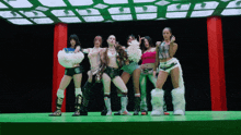 a group of women are standing on a stage with a green background