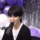 a young man is sitting in front of a microphone .