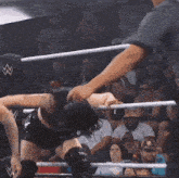 a woman in a wrestling ring with a referee and a crowd watching
