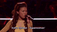 a woman singing on a stage with the words team pharrell behind her