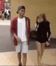 a man and a woman are standing next to each other on a sidewalk .