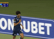 a soccer player stands in front of a sign that says ub