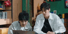 two young men are looking at a laptop computer together .