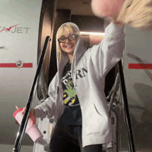 a woman wearing a hoodie that says rn is standing in front of an airplane