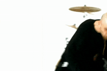 a man in a black shirt is playing drums in a blurry photo