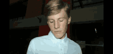 a young man wearing a white shirt looks down at something