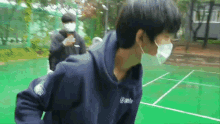 a man wearing a mask is standing on a green court