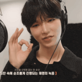 a young man wearing headphones and a black shirt is giving an ok sign