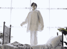 a woman in a white sweater is standing on a bed in front of a window