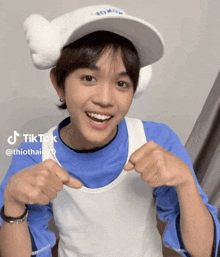 a young man wearing a white hat and a blue shirt has a tiktok sticker on his shirt
