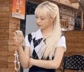 a woman with blonde hair is holding a cell phone in front of a building .