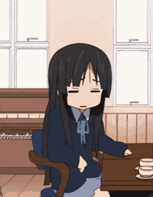 a girl with long black hair sits at a table with her eyes closed