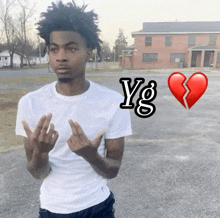 a young man in a white t-shirt is standing in a parking lot next to a broken heart and the letters yg