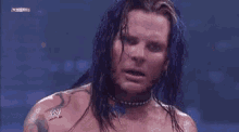a wrestler is covering his face with his hands while wearing a white glove .