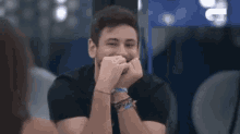 a man is laughing with his hands on his face and a woman is looking at him .