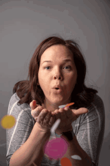 a woman blowing confetti out of her hands in front of her face