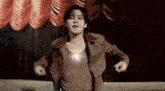 a man is dancing on a stage with a red curtain behind him .