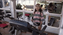 a woman is running on a treadmill in a gym with a hat on .