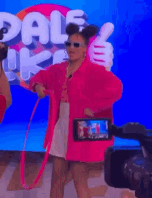 a woman in a pink coat is being filmed by a camera