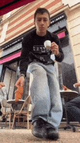a man is holding a cup of coffee in front of a store that says boutique