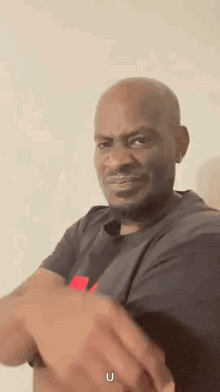 a man in a black shirt is making a funny face while holding his hands together .