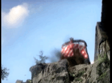 a red and white truck is driving down a rocky hillside .