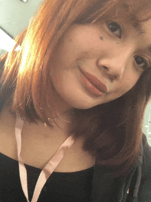 a woman with red hair and a lanyard around her neck