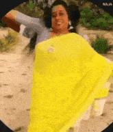 a woman in a yellow saree is dancing on a sandy beach