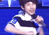 a young man is singing into a microphone while wearing a shirt with the number 8 on it .